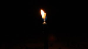 Photo of a candle flame burning against a black background