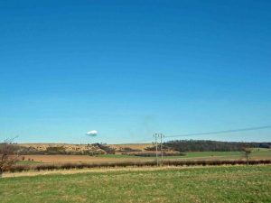 Photo of a small white cloud above green fields