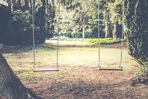 Photo of two swings on a playground.