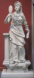 Image of woman in ancient Greek dress looking at her reflection in a hand mirror